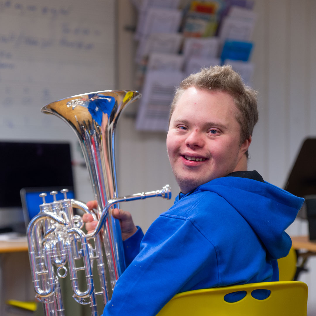 Ein smilande student, frå Musikk, bu og fritid-linja, held på instrumentet sitt