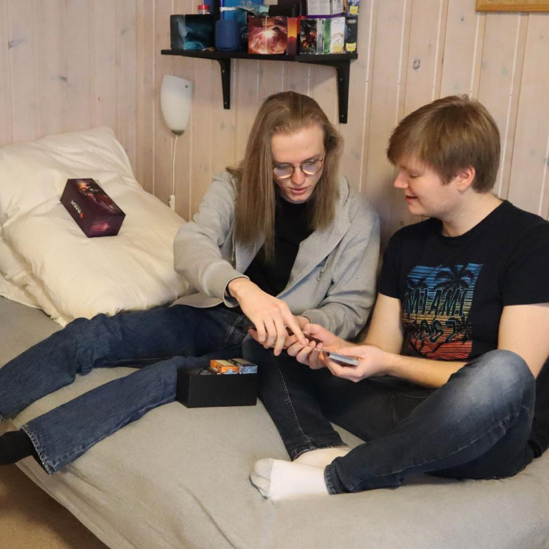 To studentar sit i senga på rommet og ser på eit spel.